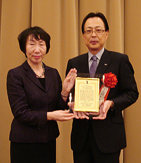 日本フィランソロピー協会の高橋理事長（左）から表彰状を授与された岡田常務（右）