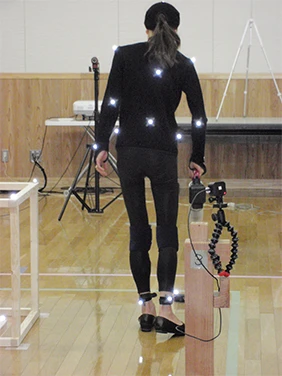 動作解析測定用のマーカーを装着してコードレス掃除機で床を掃除している様子