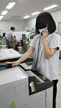 アイマスクをして備え付けのハンドセットから流れる音声に従ってマルチコピー機を操作している様子