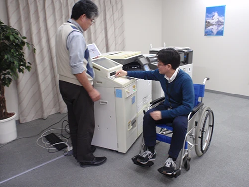 車いすを使ってデジタル複合機を操作している様子